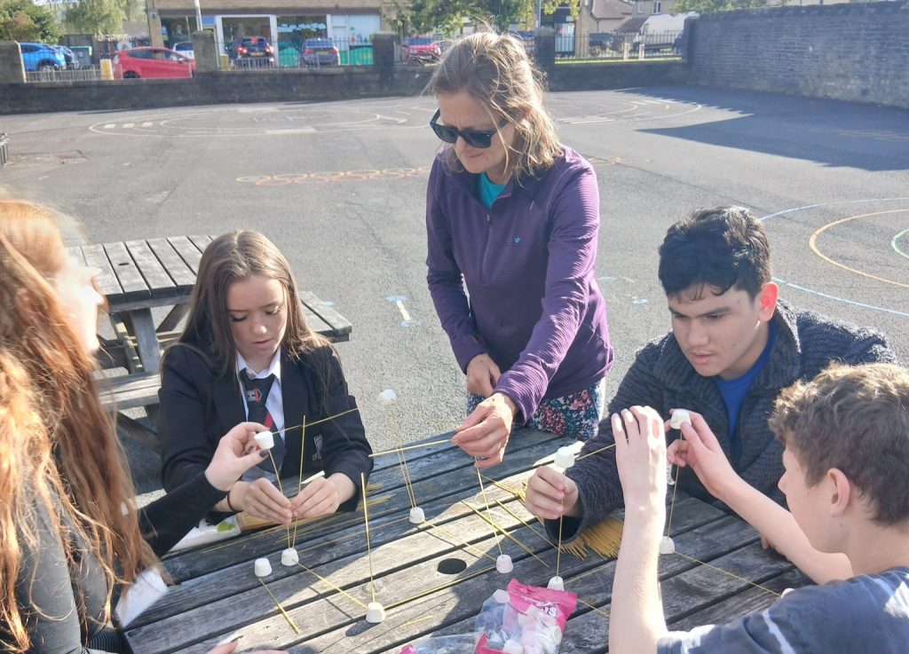 A photo of SELF volunteer Bridget helping young people with a team-building exercise.